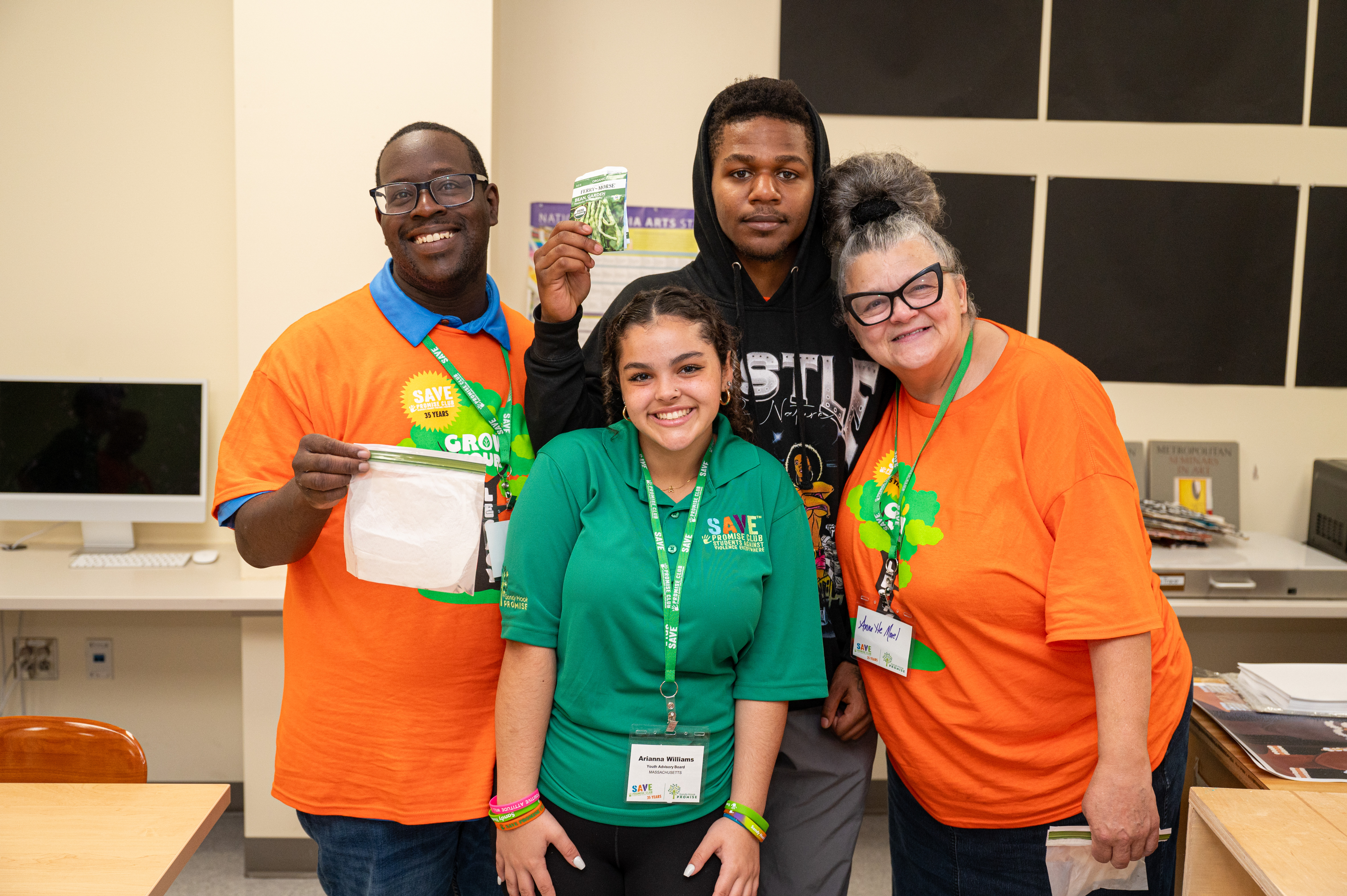 Four people standing together smiling at camera left and back people are showing off achievements