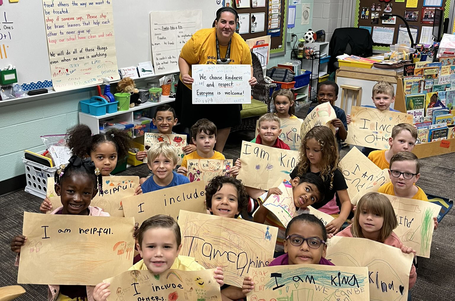 Students and teacher sitting holding signs